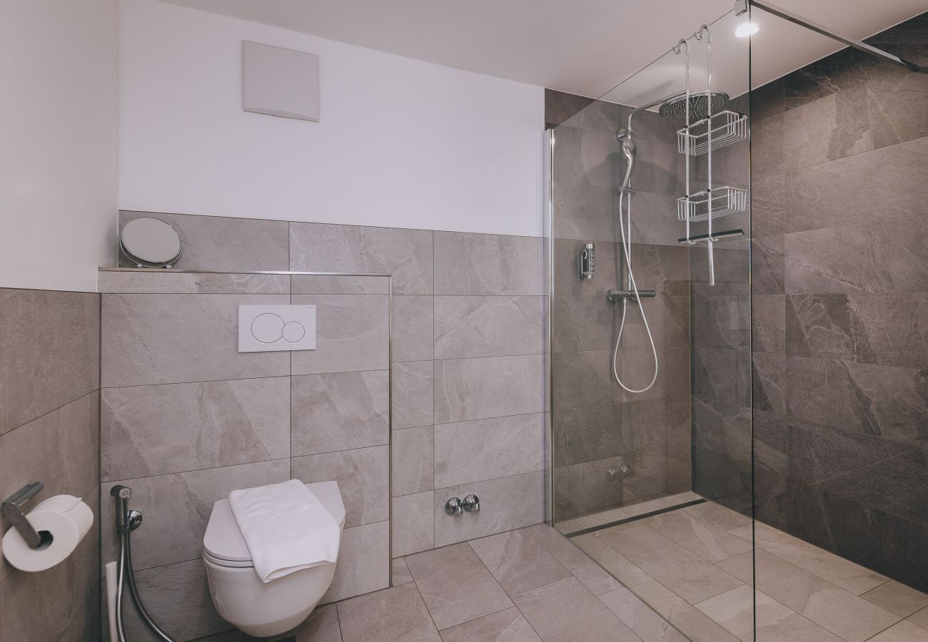 Badezimmer in Haus Altenberger Apartments by we rent. Moderne Dusche mit Doppelwaschbecken, WC, Handtuch. 