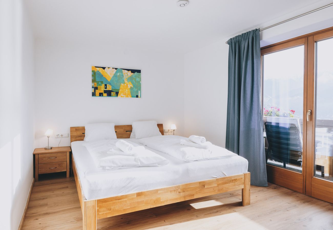 Schlafzimmer in der Ferienwohnung Haus Altenberger Apartments by we rent. Doppelbett mit Zugang zum Balkon mit Aussicht