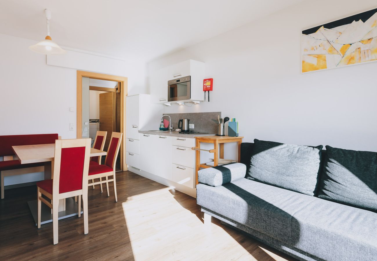 Esszimmer in der Ferienwohnung Apartments Haus Altenberger by we rent. Tisch mit Stühlen und Küche mit Herd, Ofen.